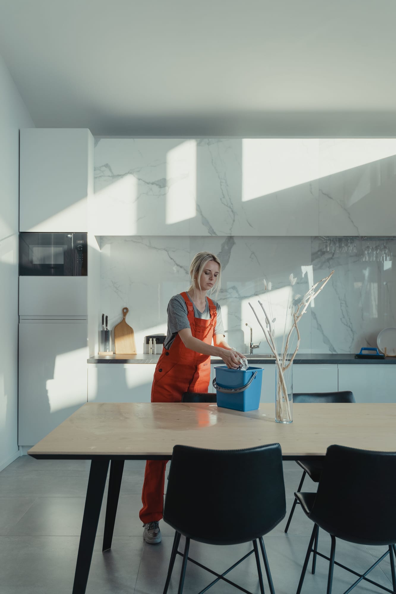 Gebäudereiniger wischt eine moderne Küchenzeile mit Eimer und Tuch