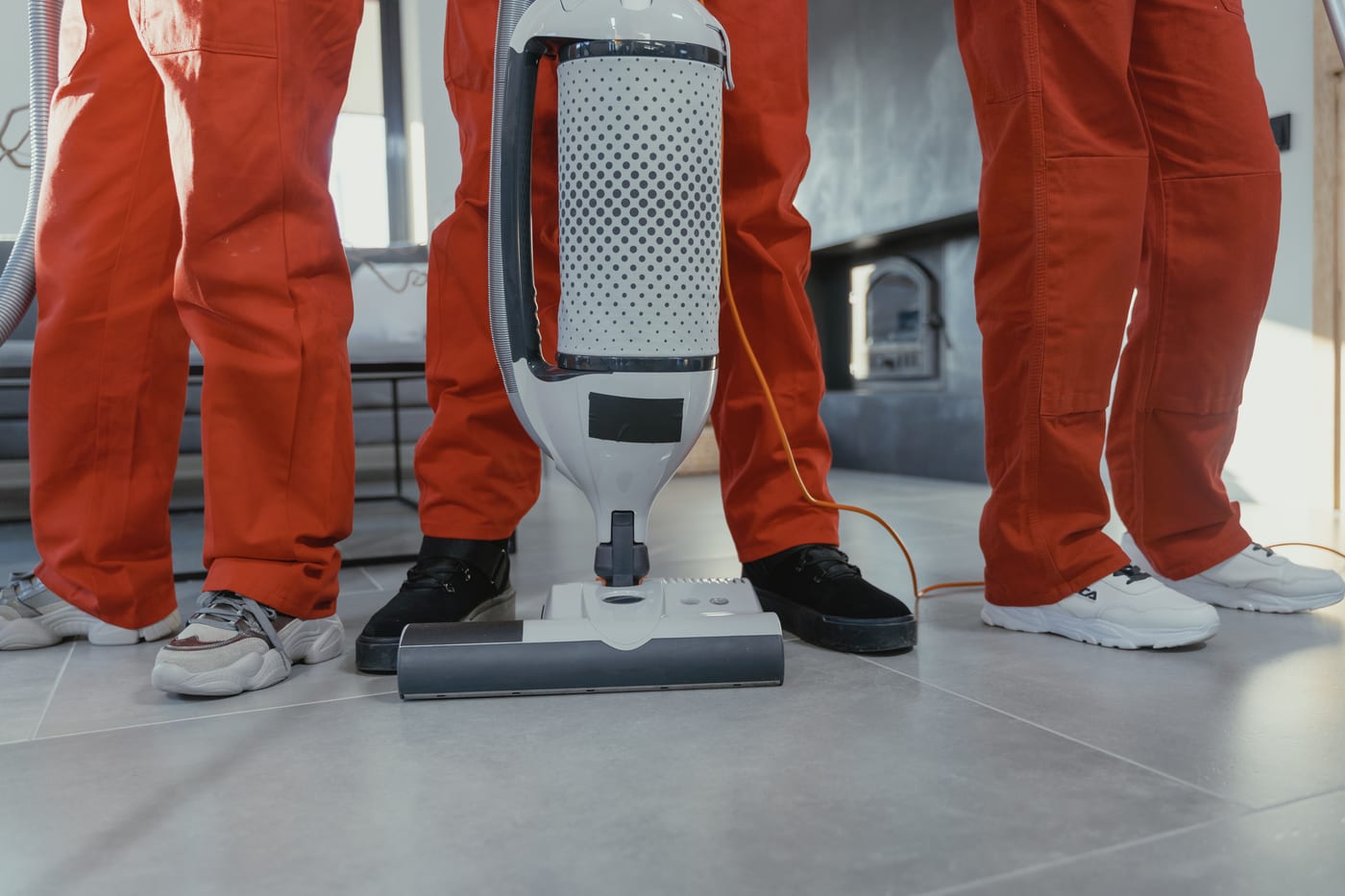 Gebäudereiniger in oranger Arbeitskleidung mit Bodenreinigungsmaschine im Büro