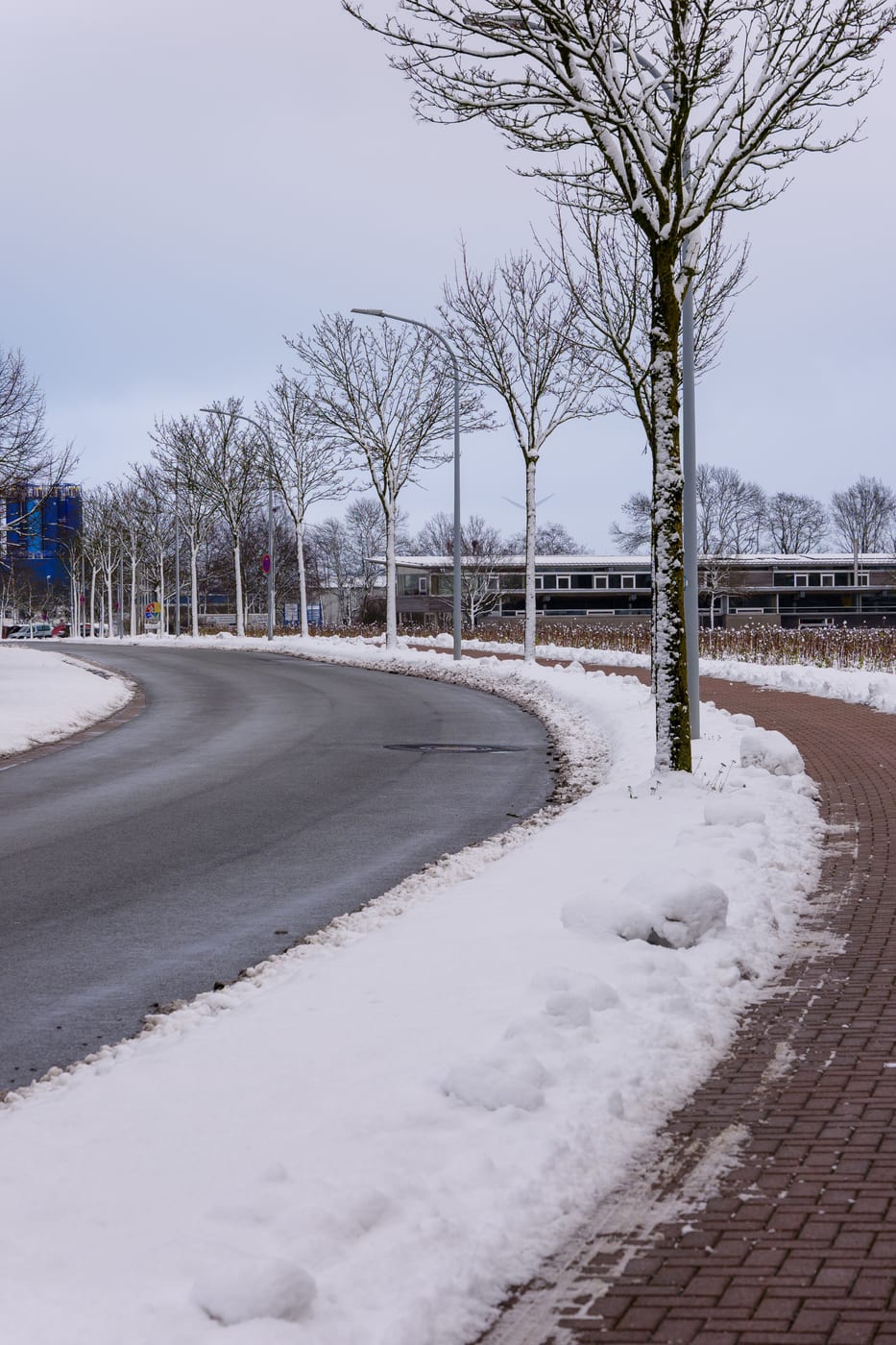Vom Hausmeister im Winterdienst geräumte Straße mit aufgeschobenen Schneewällen am Fahrbahnrand
