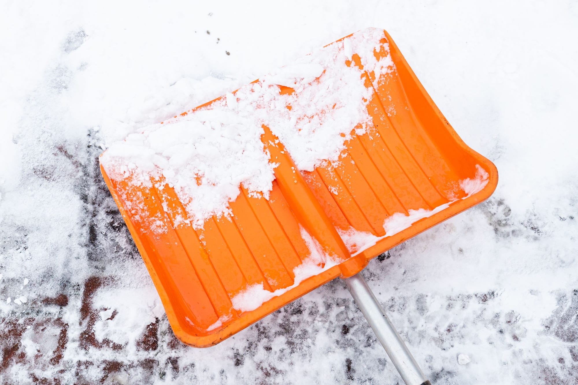 Nahaufnahme der Schneeschaufel eines Hausmeisters im Winterdiensteinsatz